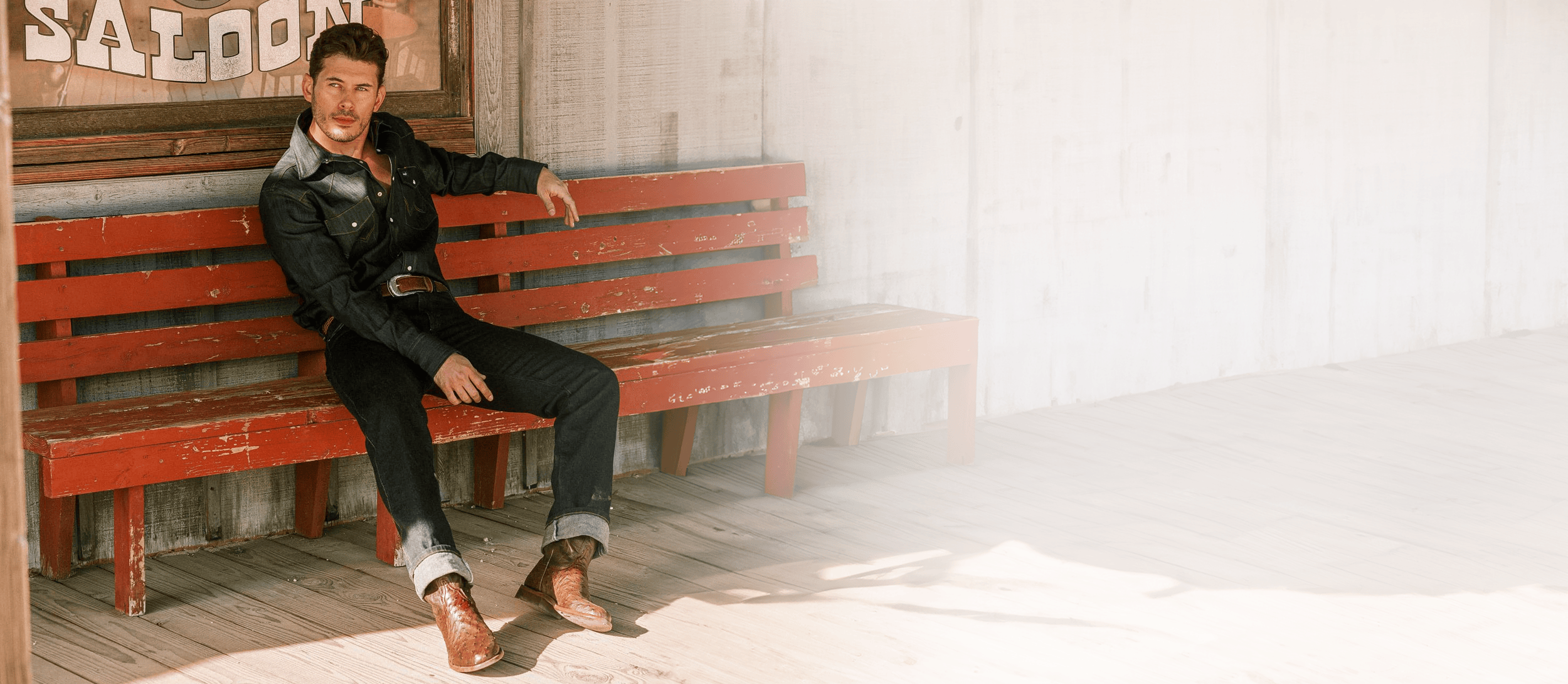 Man sitting on a bench wearing the Monterey 10” Pull-On Full Quil Western boot in chocolate. Shop the Wellington Collection.